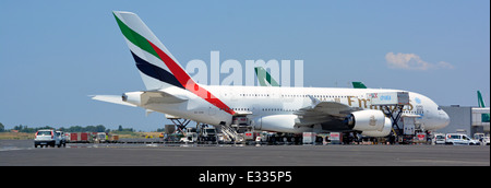 Emirates airline logo Airbus A380 double decker wide body four engine jet airplane airport apron stand ground crew attend Rome Fiumicino Airport Italy Stock Photo
