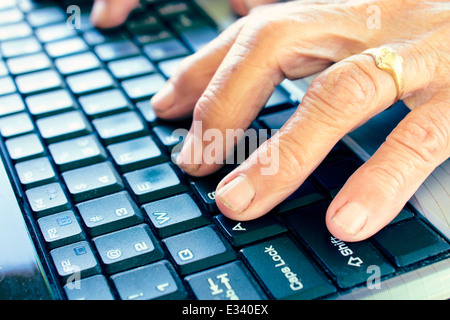 Old female hands typing on the computer keyboard.Selective focus on front finger Stock Photo