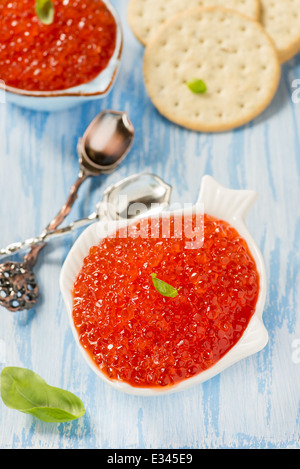 Red caviar in fish-shape bowl with crackers, closeup, selective focus Stock Photo