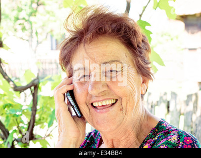 Old lady using mobile phone and have smile on her face Stock Photo