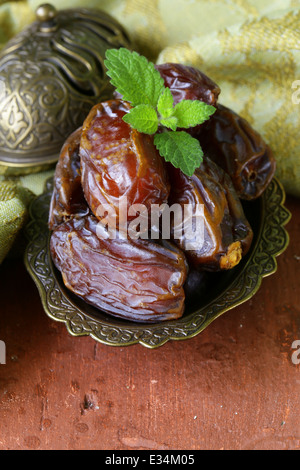 sweet dried dates in bowl on a wooden table Stock Photo