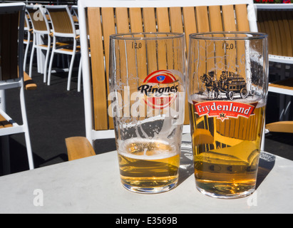 Half full and nearly empty beer glasses , two major Norwegian brands Ringnes and Frydenlund, popular outdoors in the summer sun Stock Photo