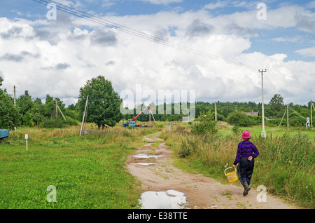 Rural lifestyle 2013. The woman picked berries in the wood and go home. Stock Photo