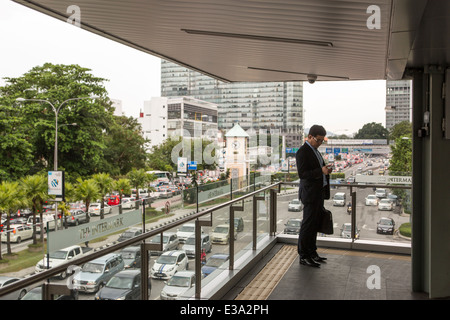 A business man looks at his smart phone in Kuala Lumpur, Malaysia Stock Photo