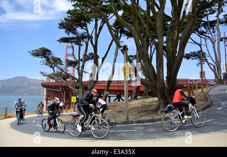 cyclists on rental bikes riding on bike path leading up to Golden Gate Bridge Stock Photo