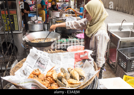 A woman fries fish outside a restaurant in Kuala Lumpur, Malaysia Stock Photo