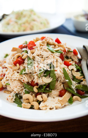 Closeup of plate of noodle salad with cashew nuts and cherry tomatoes and green peas Stock Photo