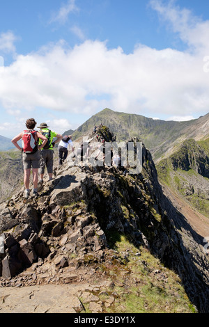 Scramblers climbing on Crib Goch mountain ridge top scramble path on Snowdon Horseshoe with Mount Snowdon peak in distance. Snowdonia North Wales UK Stock Photo