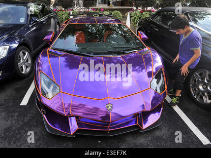 Passers-by stop to check out two flashy cars parked outside the front of The Dorchester Hotel. A purple Lamborghini Aventador and yellow and gold Bugatti Veyron.  Featuring: Lamborghini Aventador Where: London, United Kingdom When: 20 Oct 2013 Stock Photo