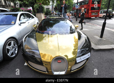 Passers-by stop to check out two flashy cars parked outside the front of The Dorchester Hotel. A purple Lamborghini Aventador and yellow and gold Bugatti Veyron.  Featuring: Bugatti Veyron Where: London, United Kingdom When: 20 Oct 2013 Stock Photo