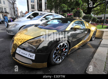 Passers-by stop to check out two flashy cars parked outside the front of The Dorchester Hotel. A purple Lamborghini Aventador and yellow and gold Bugatti Veyron.  Featuring: Bugatti Veyron Where: London, United Kingdom When: 20 Oct 2013 Stock Photo