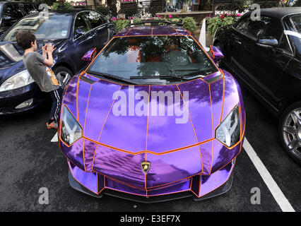 Passers-by stop to check out two flashy cars parked outside the front of The Dorchester Hotel. A purple Lamborghini Aventador and yellow and gold Bugatti Veyron.  Featuring: Lamborghini Aventador Where: London, United Kingdom When: 20 Oct 2013 Stock Photo