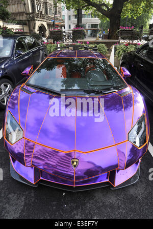 Passers-by stop to check out two flashy cars parked outside the front of The Dorchester Hotel. A purple Lamborghini Aventador and yellow and gold Bugatti Veyron.  Featuring: Lamborghini Aventador Where: London, United Kingdom When: 20 Oct 2013 Stock Photo