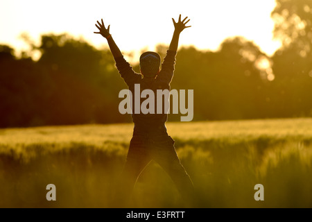 Little Boy Freedom jumping in wheat field at sunset Stock Photo