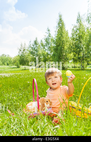 Happy boy with rabbit sitting on green grass Stock Photo