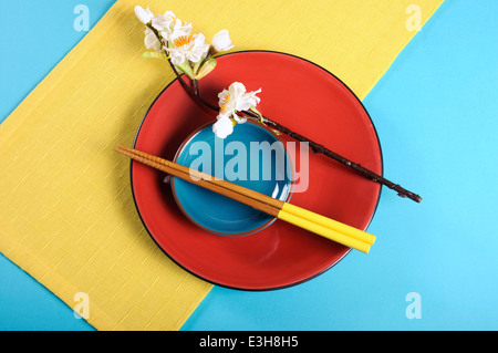 Modern take on traditional Japanese oriental place setting with colorful chopsticks and red, yellow and aqua blue color blocking Stock Photo