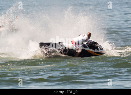 Man on Sea Doo trying to miss his flyboarder who has just entered the water. Stock Photo