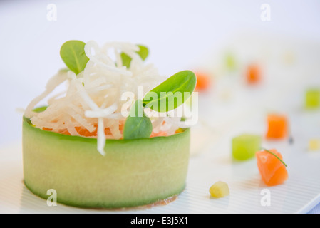 Salmon, wrapped in cucumber, topped with rice noodles. Stock Photo