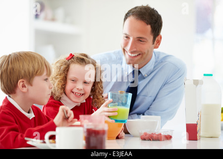 Father And Children Having Breakfast In Kitchen Together Stock Photo