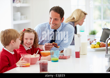 Family Having Breakfast In Kitchen Before School And Work Stock Photo