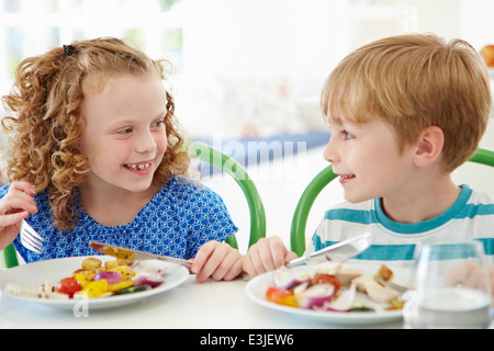 Two Children Eating Meal At Home Together Stock Photo