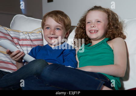 Two Children Sitting On Sofa Watching TV Together Stock Photo
