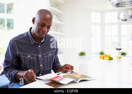 African American Man Reading Magazine At Home Stock Photo