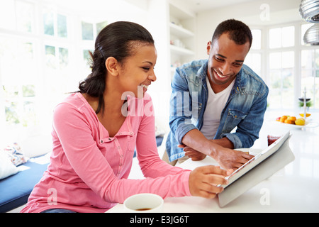 Couple Having Breakfast And Using Digital Tablet In Kitchen Stock Photo