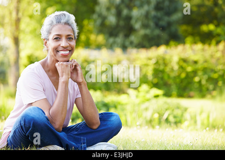 Attractive Mature Woman Sitting In Garden Stock Photo