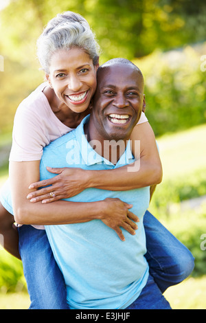 Mature Man Giving Woman Piggyback In Countryside Stock Photo