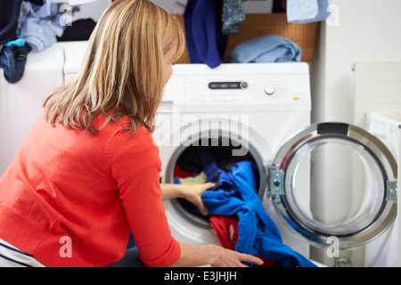 Woman Loading Clothes Into Washing Machine Stock Photo