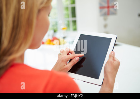 Woman Using Digital Tablet At Home In Kitchen Stock Photo