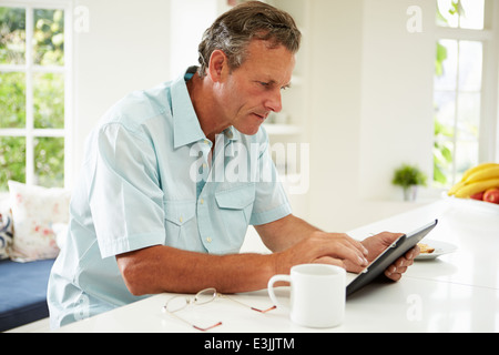 Middle Aged Man Using Digital Tablet Over Breakfast Stock Photo