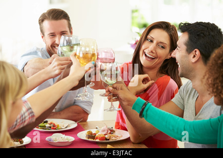 Group Of Friends Making Toast Around Table At Dinner Party Stock Photo