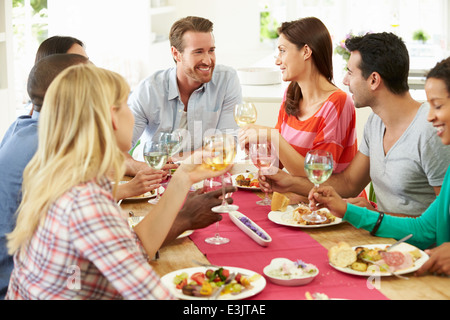 Group Of Friends Making Toast Around Table At Dinner Party Stock Photo