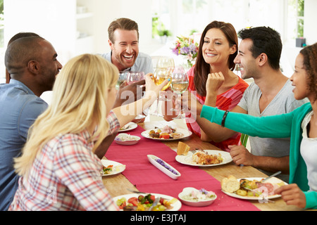 Group Of Friends Making Toast Around Table At Dinner Party Stock Photo