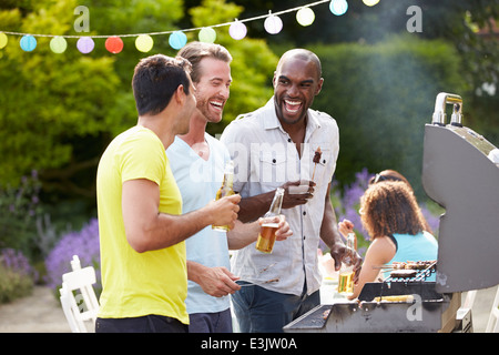 Group Of Men Cooking On Barbeque At Home Stock Photo