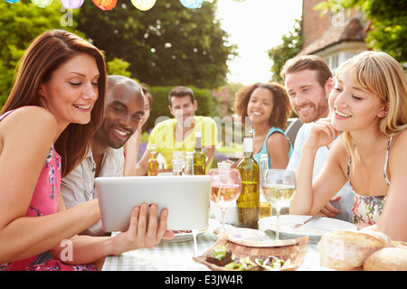 Friends Having Barbeque At Home Looking At Digital Tablet Stock Photo