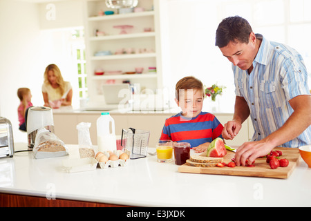 Son Helping Father To Prepare Family Breakfast In Kitchen Stock Photo