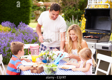 Family Enjoying Outdoor Barbeque In Garden Stock Photo