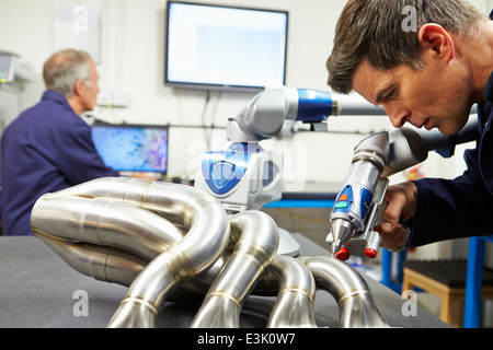 Two Engineers Using Computerized CMM Arm In Factory Stock Photo