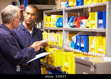 Worker And Apprentice Checking Stock Levels In Store Room Stock Photo
