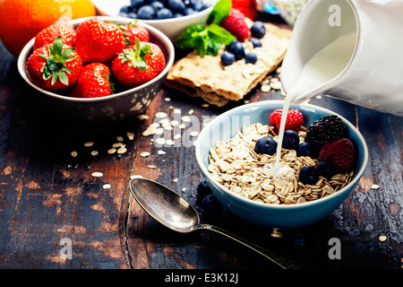 diet breakfast - bowls of oat flake, berries and fresh milk on wooden background - health and diet concept Stock Photo