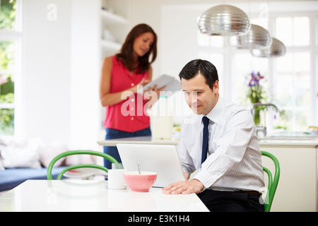 Couple Using Digital Devices At Breakfast Table Stock Photo