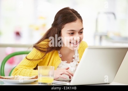 Hispanic Girl Using Laptop Eating Breakfast Stock Photo