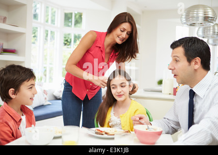 Family Having Breakfast Before Husband Goes To Work Stock Photo