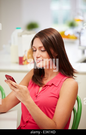 Hispanic Woman Sending Text Message At Home Stock Photo