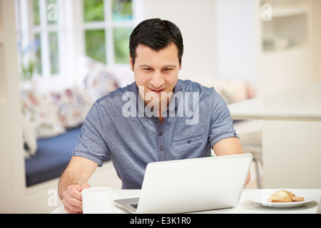 Hispanic Man Using Laptop In Kitchen At Home Stock Photo