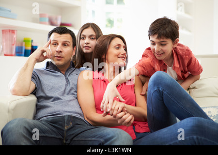 Hispanic Family Sitting On Sofa Watching TV Together Stock Photo