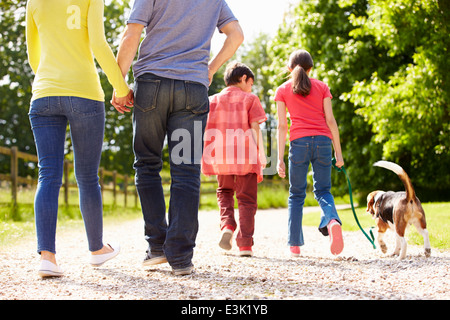 Rear View Of Family Taking Dog For Walk In Countryside Stock Photo